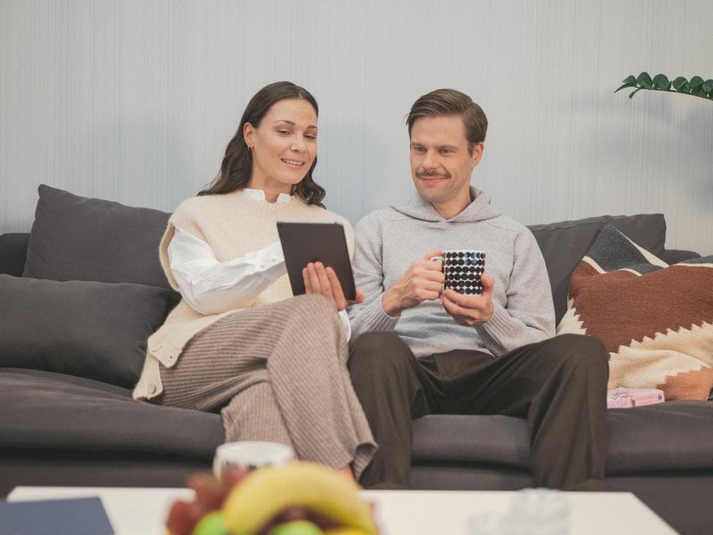Mees ja naine istuvad koos diivanil, mõlemad keskendunud käes olevale tahvelarvutile