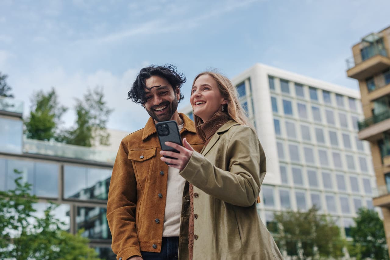 Mees ja naine naeratavad, tehes selfie moodsas hoones